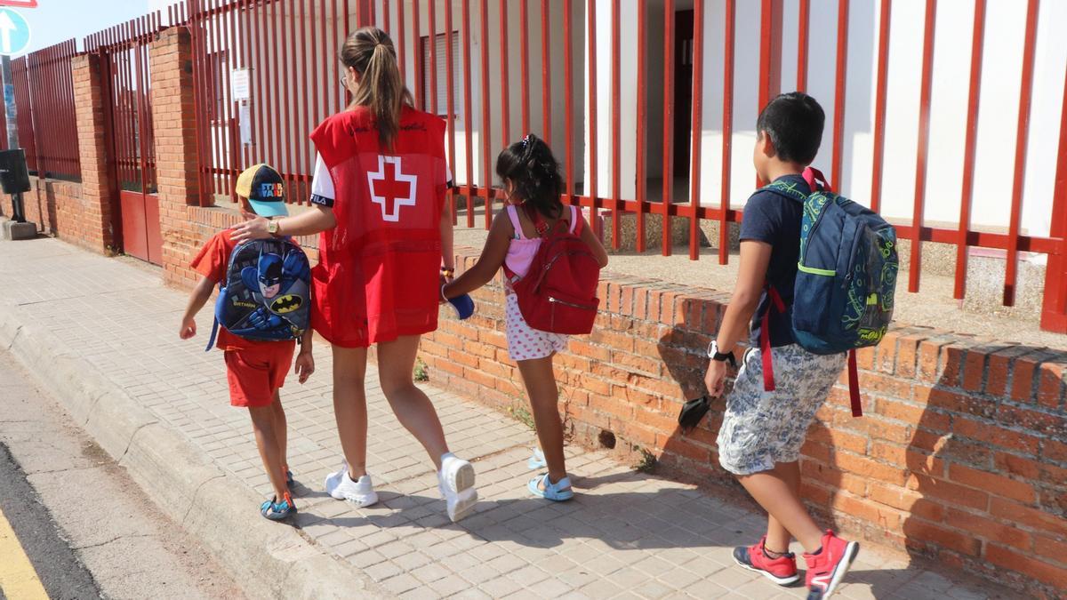 Una voluntaria de Cruz Roja acompaña a unos niños a una actividad.