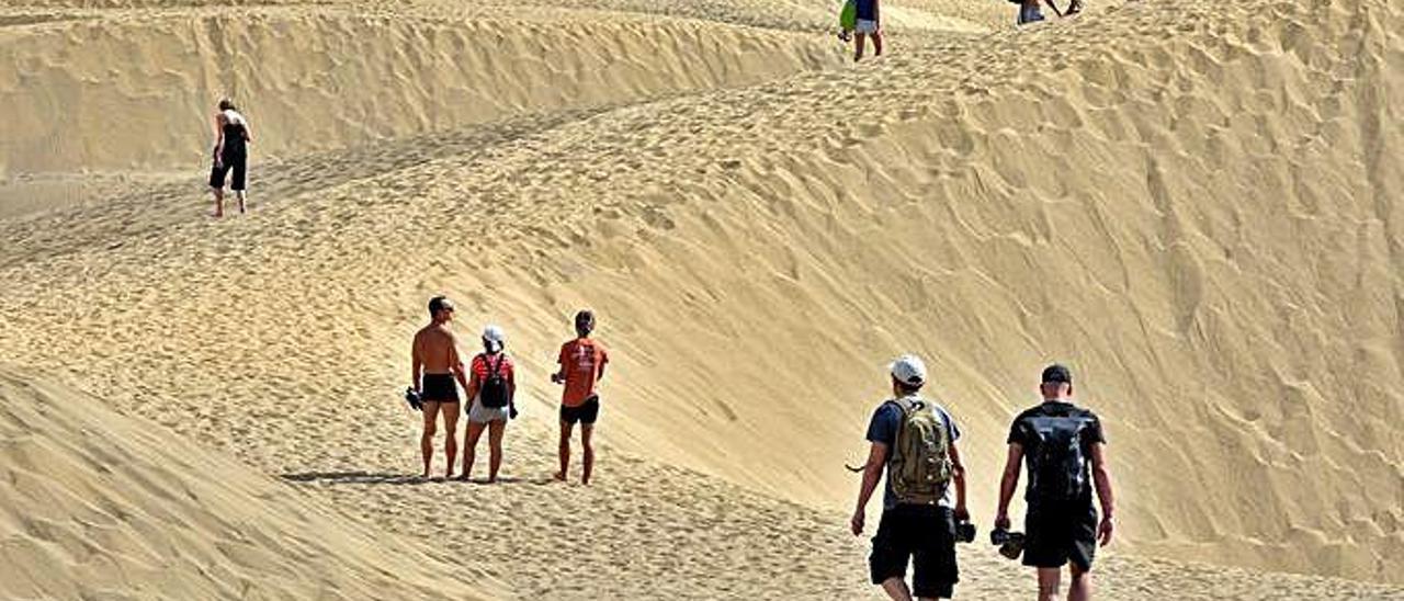 Un grupo de turistas camina por las Dunas de Maspalomas, en el Sur de Gran Canaria.