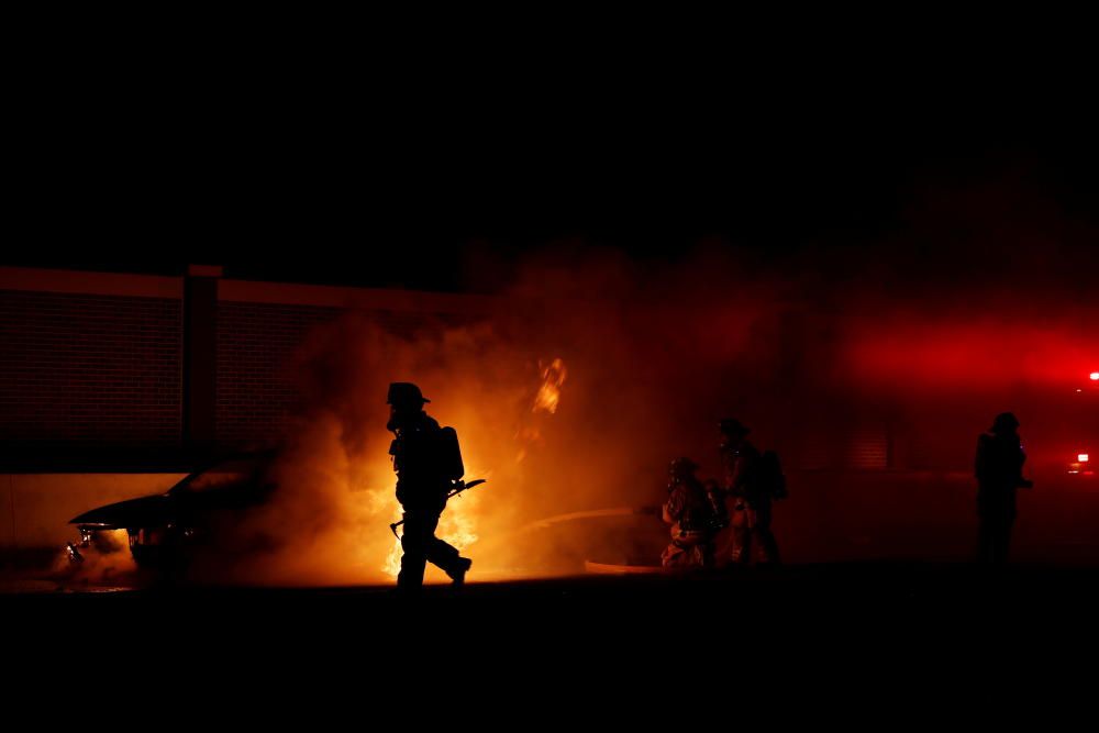 Firemen work to distinguish a car fire on ...