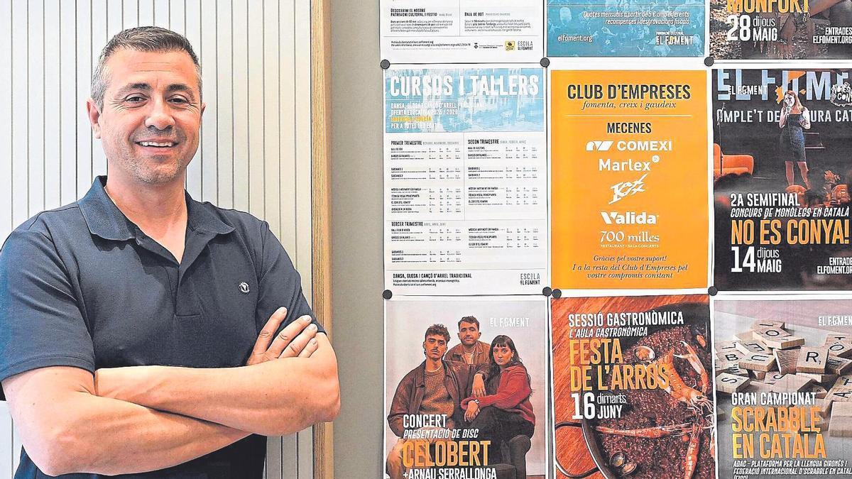 Candi Granés, a l’entrada de l’escola d’El Foment, amb cartells anunciant un munt d’activitats.
