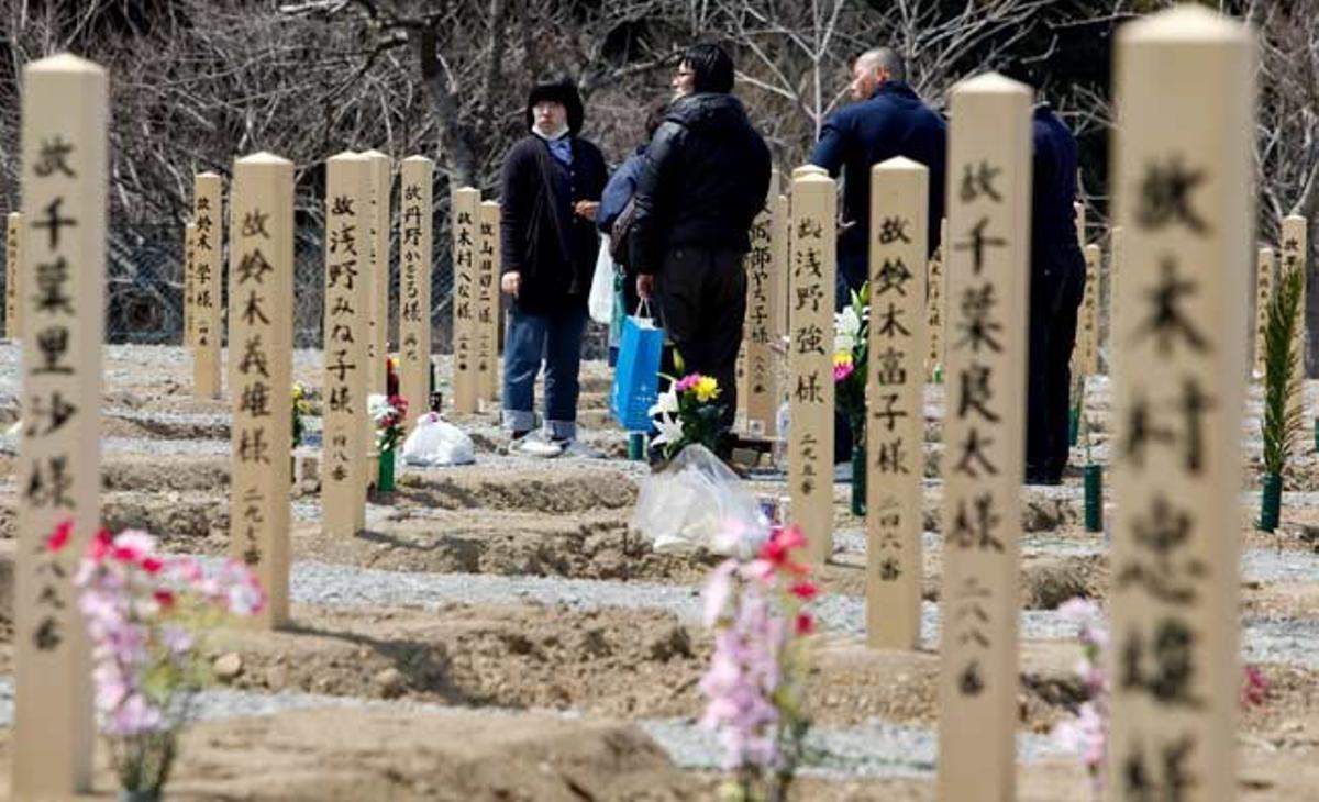 Una família visita la tomba dels familiars que van morir en el terratrèmol i posterior tsunami de l’11 de març del 2011, a la localitat d’Onagawa, prefectura de Miyagi, al nord-est del Japó.