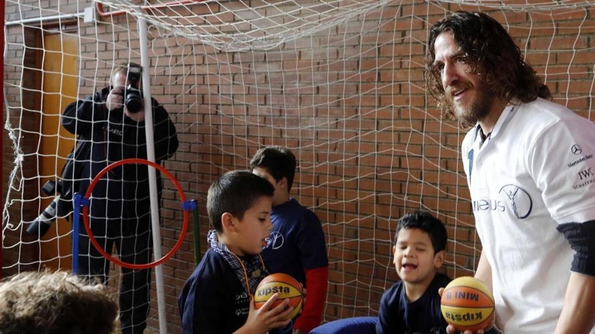 El exjugador Carles Puyol juega con unos niños en el gimnasio del colegio especial Princesa Sofía de Madrid (2015)