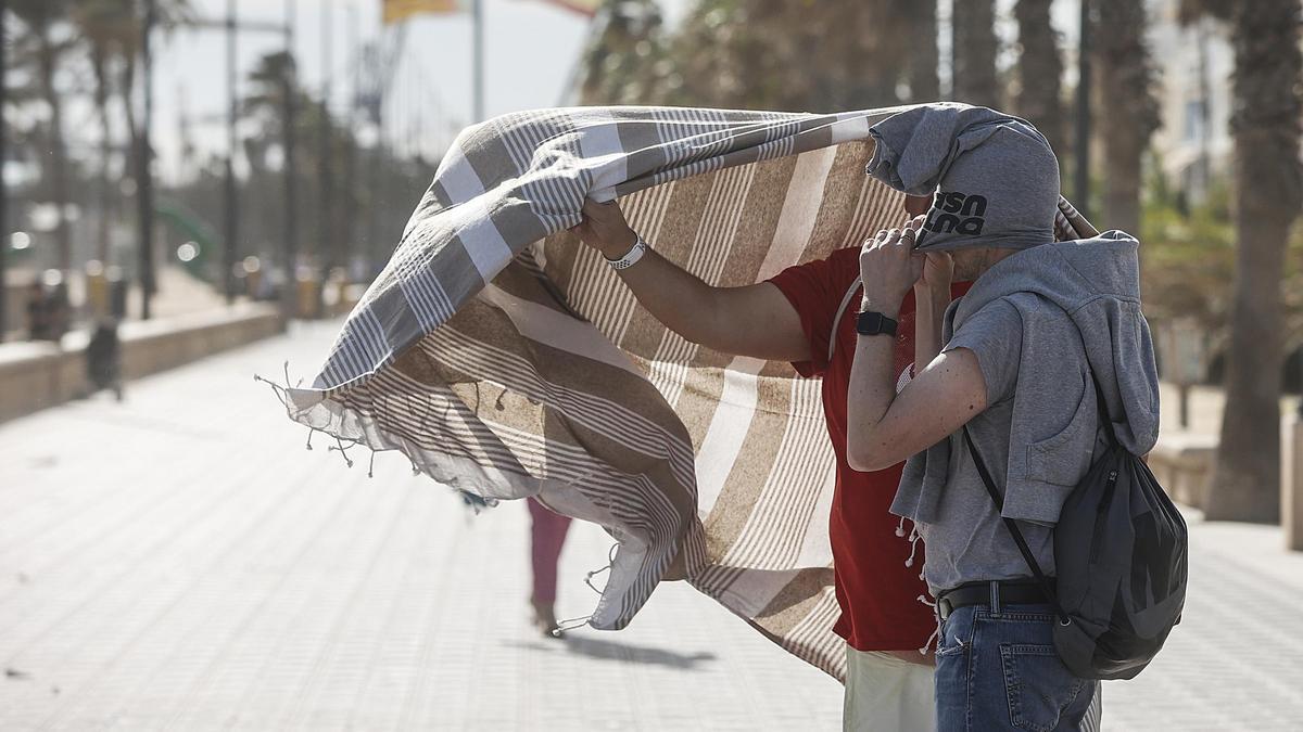 Dos personas se cubren para combatir el fuerte viento