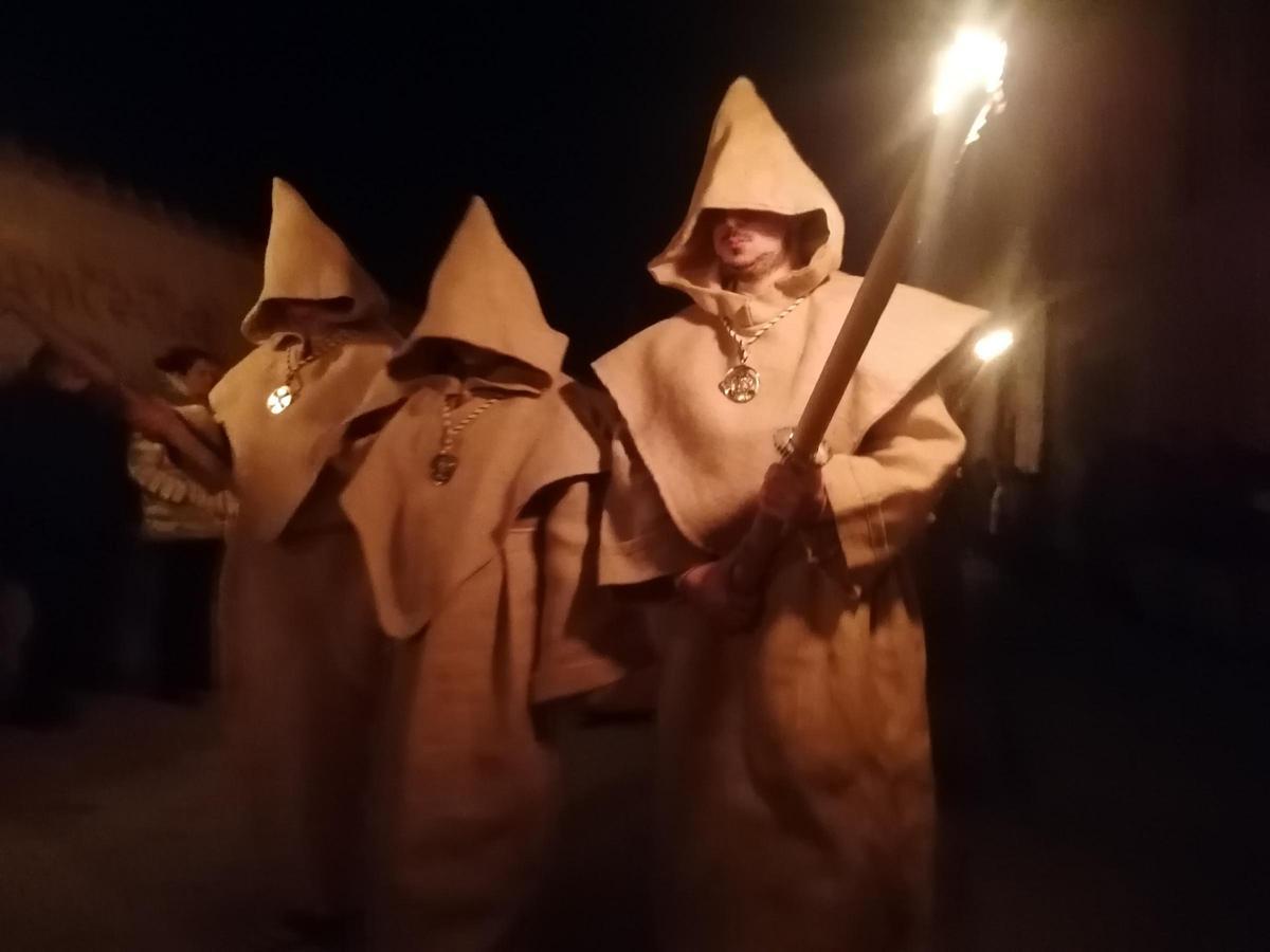 Tres hermanos de la Asociación procesionan alumbrados por las teas.