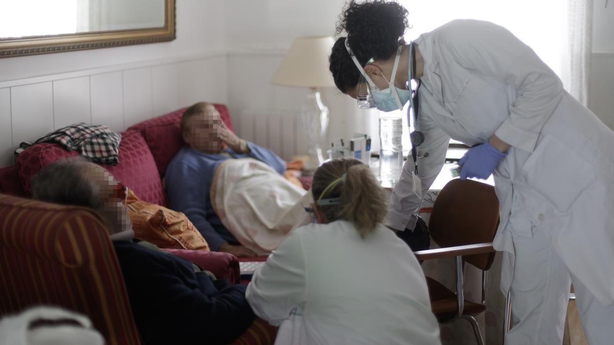 Una médico residente atiende a domicilio a una paciente junto a una compañera.