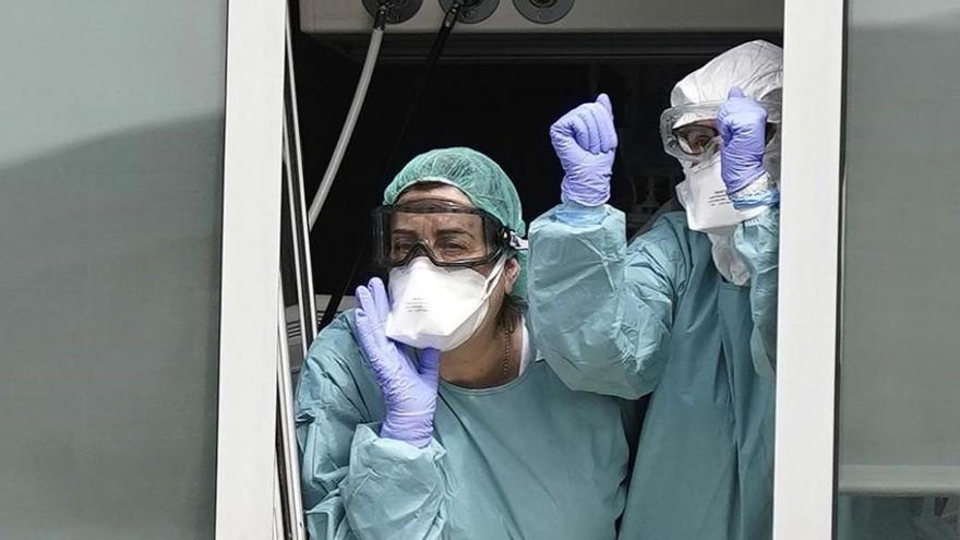 Dos sanitarios del madrileño Hospital de La Paz saludan al público que les anima desde el exterior.