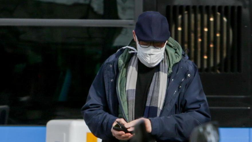 Un hombre anda por la calle llevando una mascarilla.