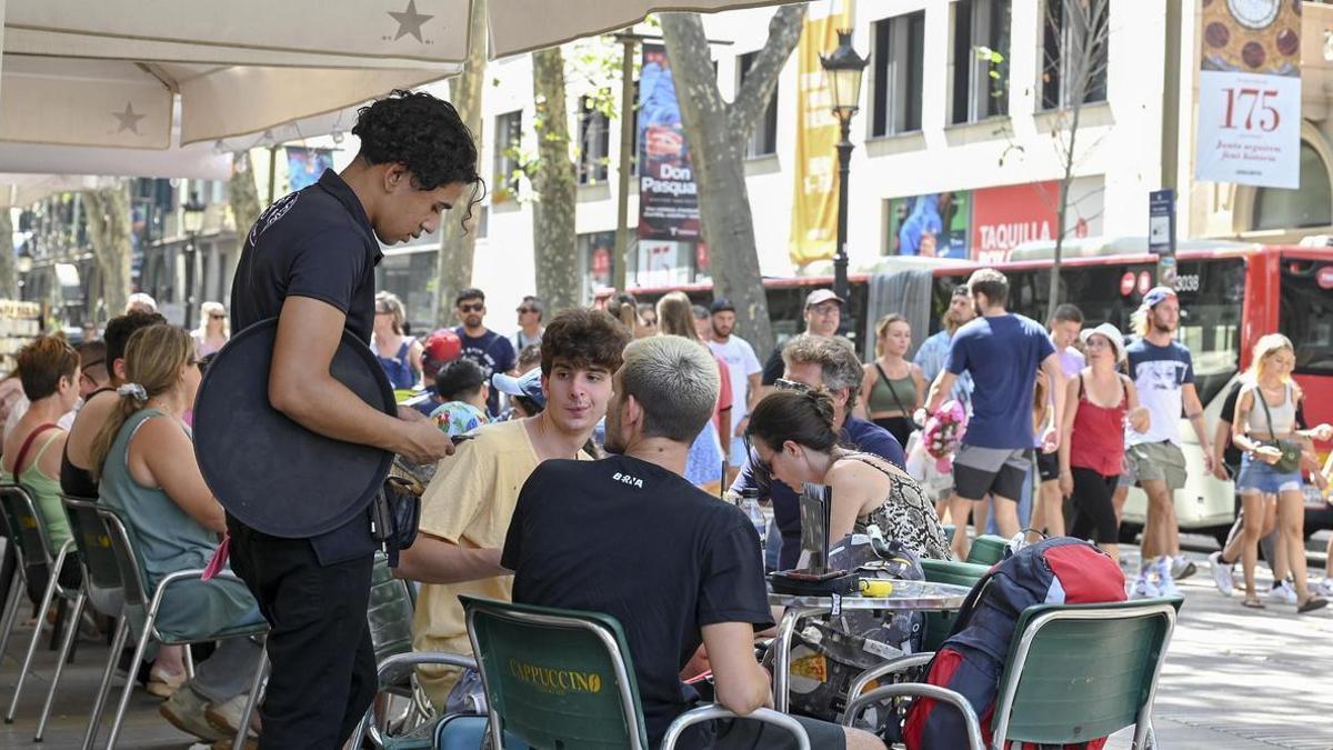 Un camarero cobra con tarjeta a unos clientes en una terraza de Barcelona.