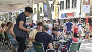 Un camarero cobra con tarjeta a unos clientes en una terraza frente al Liceu, en Barcelona.