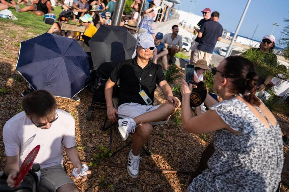 Visitantes y aficionados a la observación astronómica esperan en el Port de la Maria, en Tarragona, para contemplar el eclipse total de Sol.