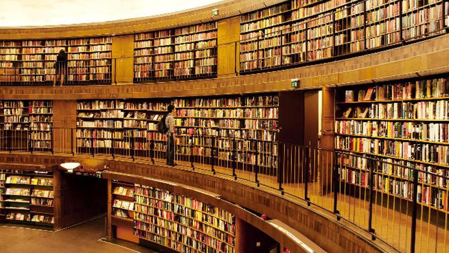 Varios usuarios consultan libros en una gran biblioteca.