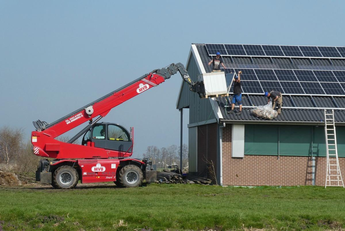 Varios operarios instalan paneles solares en un edificio.