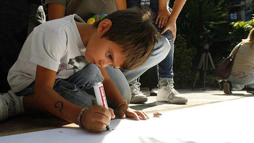 Un niño contribuye en el poema gigante que se realizó ayer en la plaza de Gabriel Miró