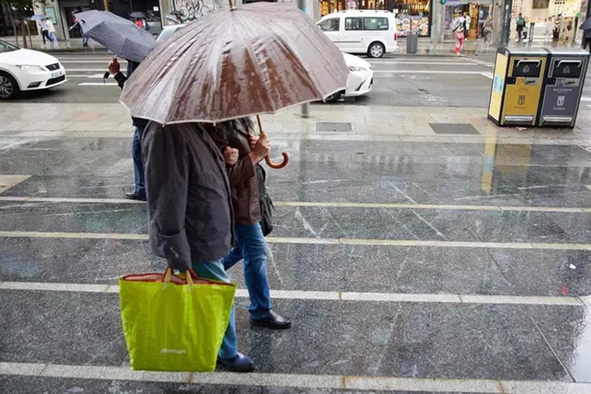 personas con paraguas caminan bajo la lluvia por el centro de Madrid.