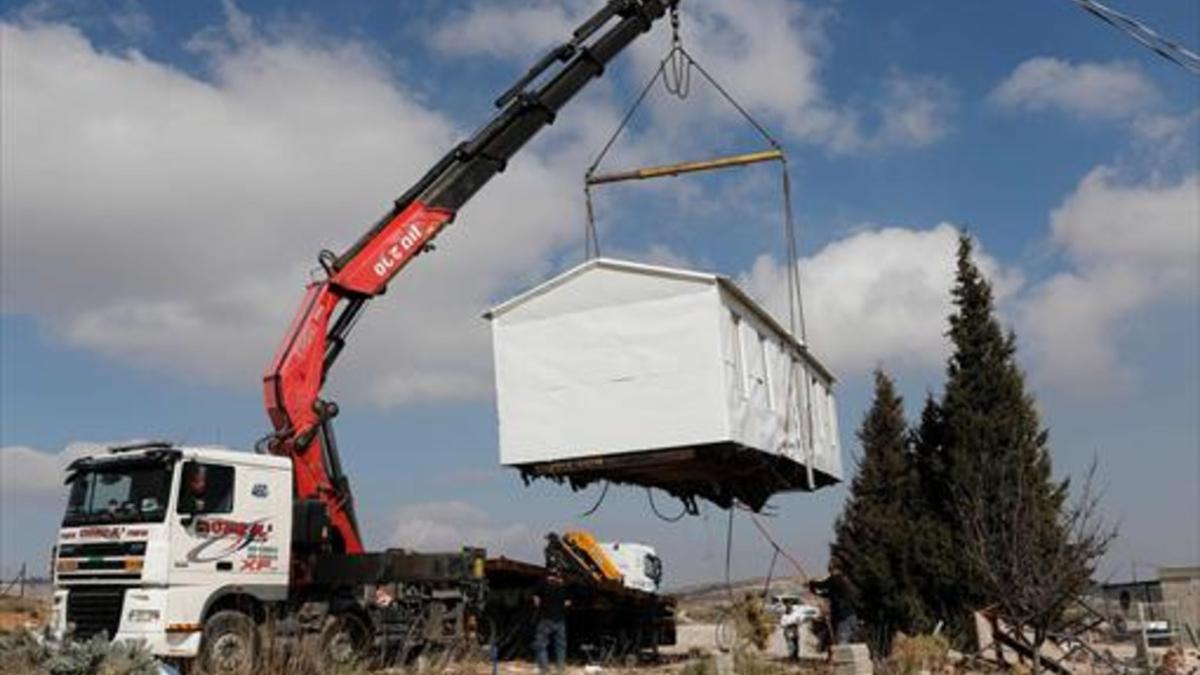 Una grúa levanta, ayer, una casa prefabricada del asentamiento de Amona, desmantelado por Israel.