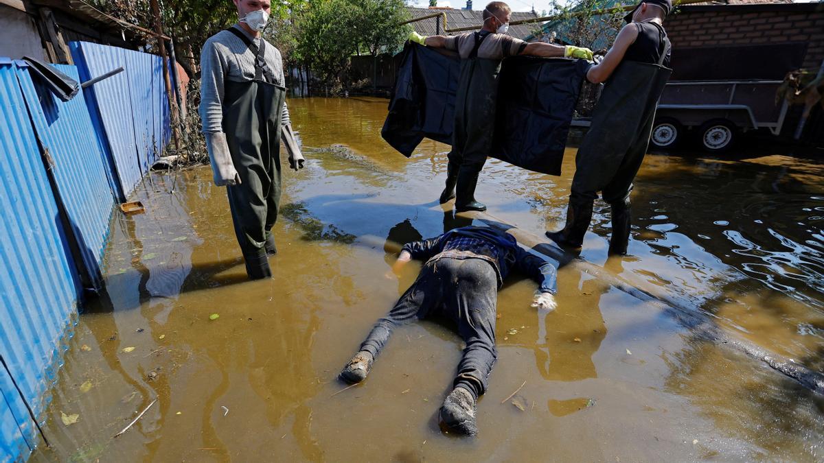 Voluntarios y trabajadores municipales recuperan el cuerpo de una casa inundada después de que las aguas retrocedieran tras el colapso de la represa Nova Kakhovka en el curso del conflicto Rusia-Ucrania