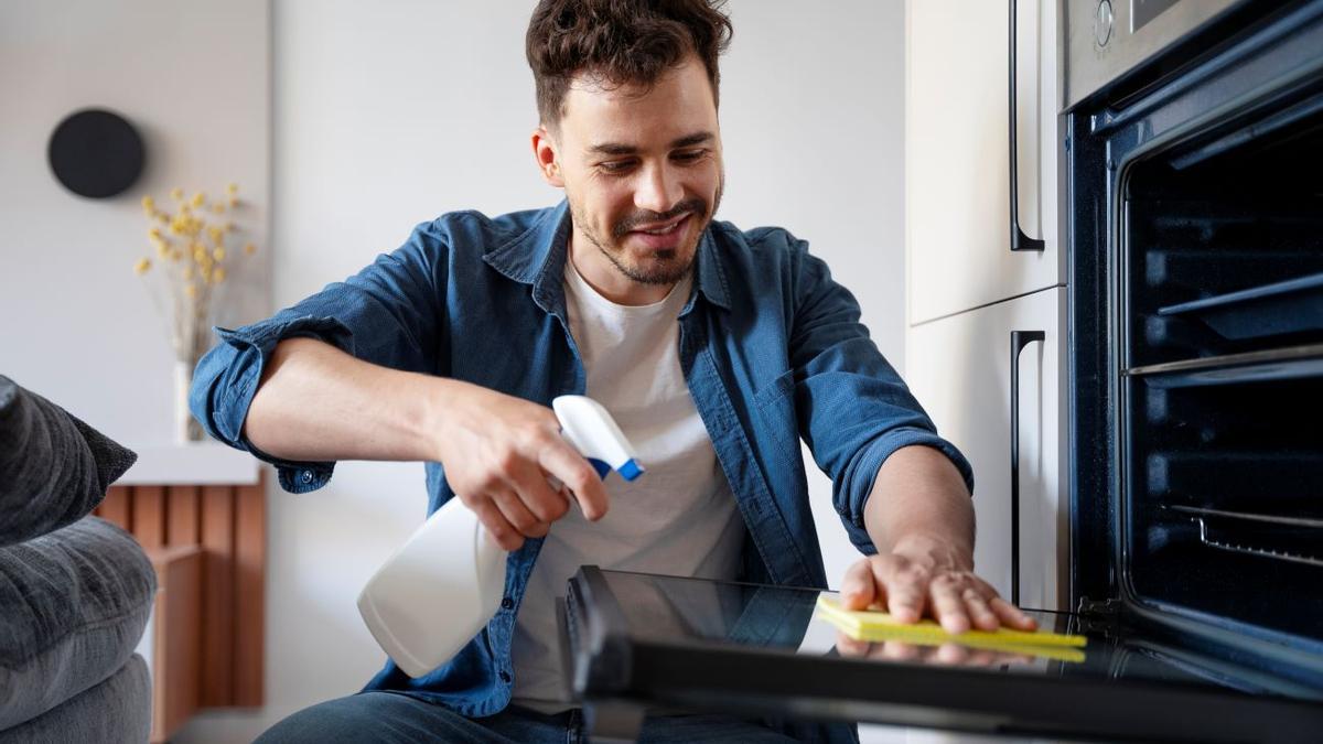 Un hombre limpiando la puerta del horno de casa