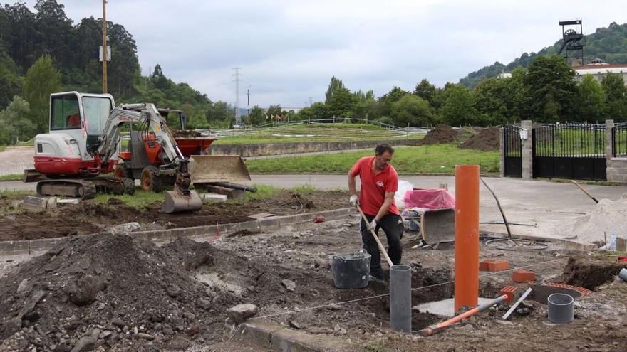 Las obras en el nuevo parque de autocaravanas de El Entrego, con el Museo de la Minería al fondo. | Zai Semeyes