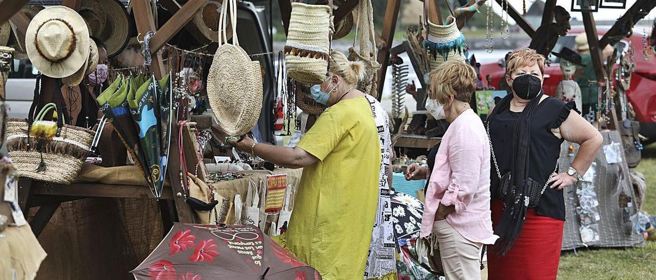 Varias mujeres curiosean en uno de los puestos de artesanía. | Ricardo Solís