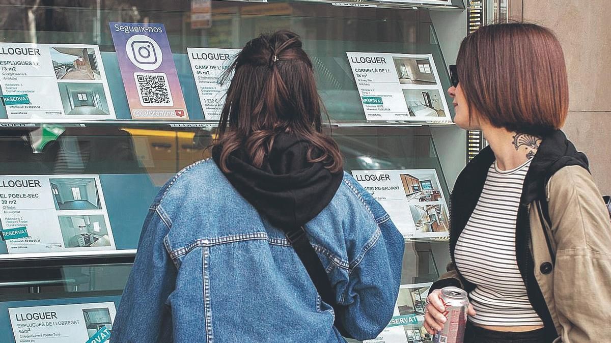 Dos chicas jóvenes buscan ofertas de alquiler en una inmobiliaria de Barcelona Dos chicas jóvenes buscan ofertas de alquiler en una inmobiliaria de Barcelona