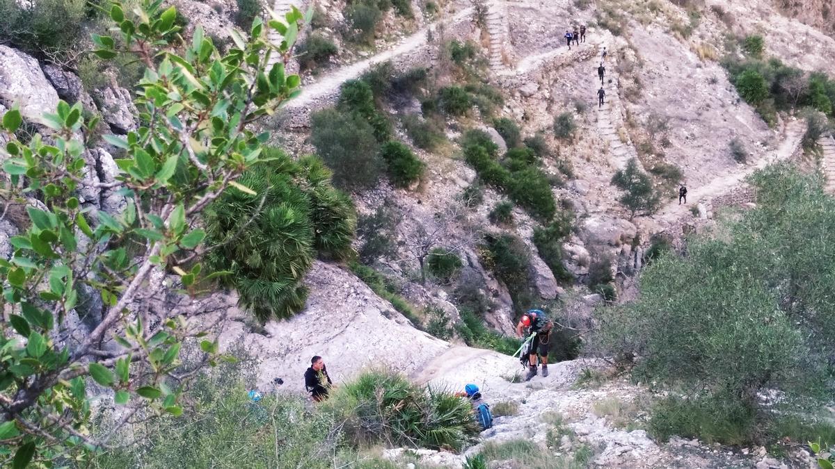 Escaladores se descuelgan por el salto de agua de Fleix, ahora seco, y, al fondo, los senderistas