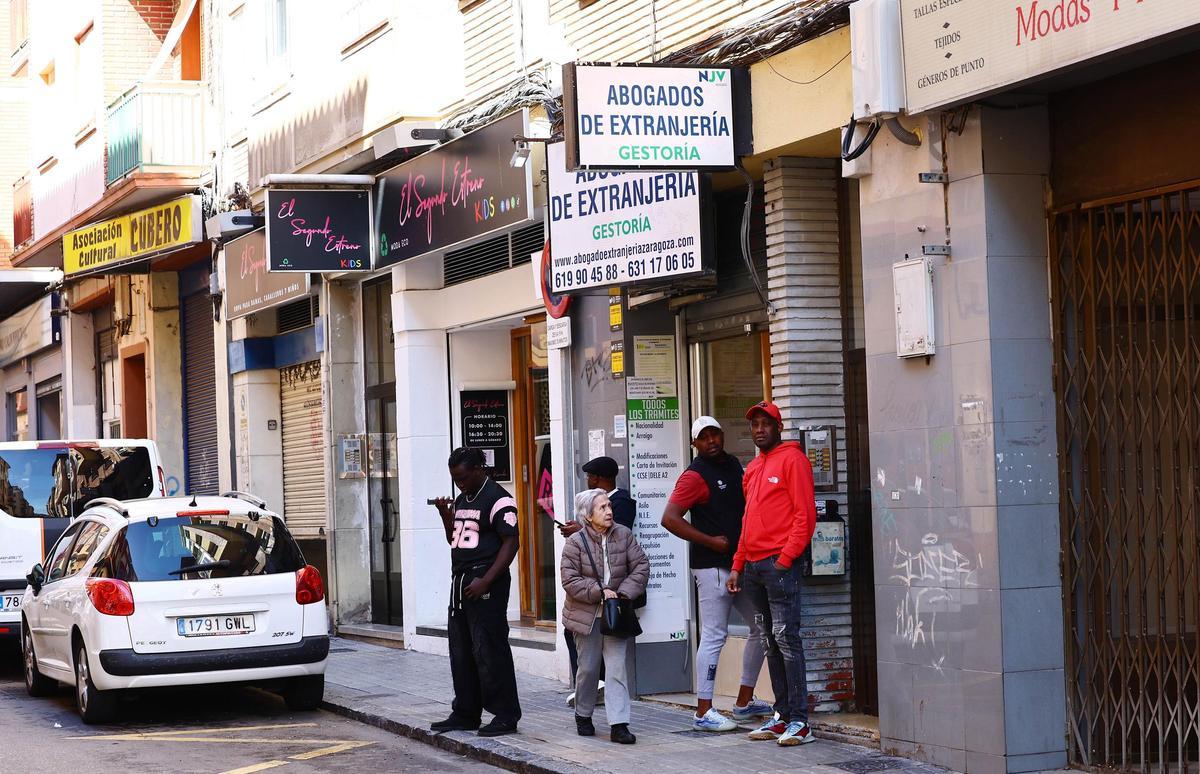 Un grupo de migrante en la entrada de un bufete de abogados especializado en extranjería en el barrio de Delicias de Zaragoza.