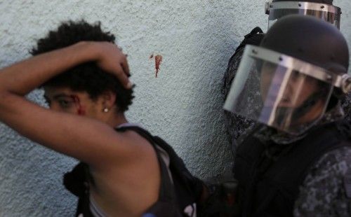 A wounded demonstrator is detained by riot police during a protest against the 2014 World Cup in Sao Paulo