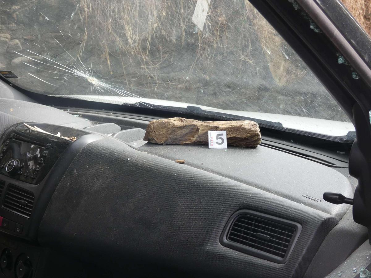 Un vidre trencat i la pedra usada per rebentar els vidres del cotxe a Planoles.