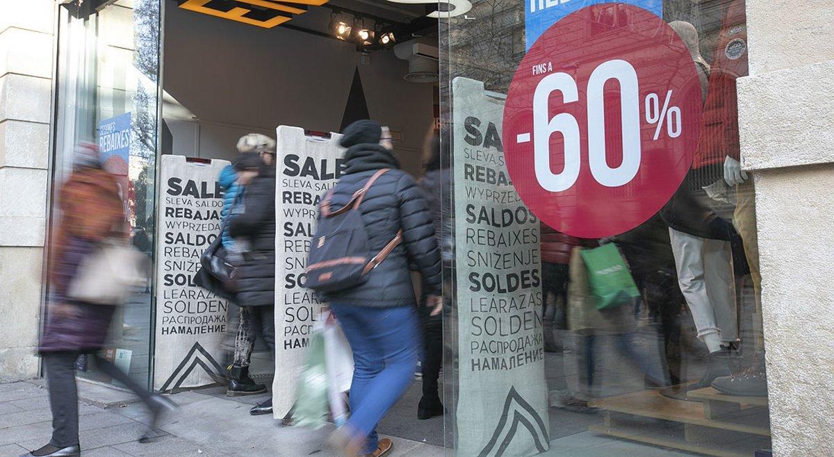 Carteles de rebajas en una tienda de moda del Portal de l’Àngel de Barcelona, este sábado.