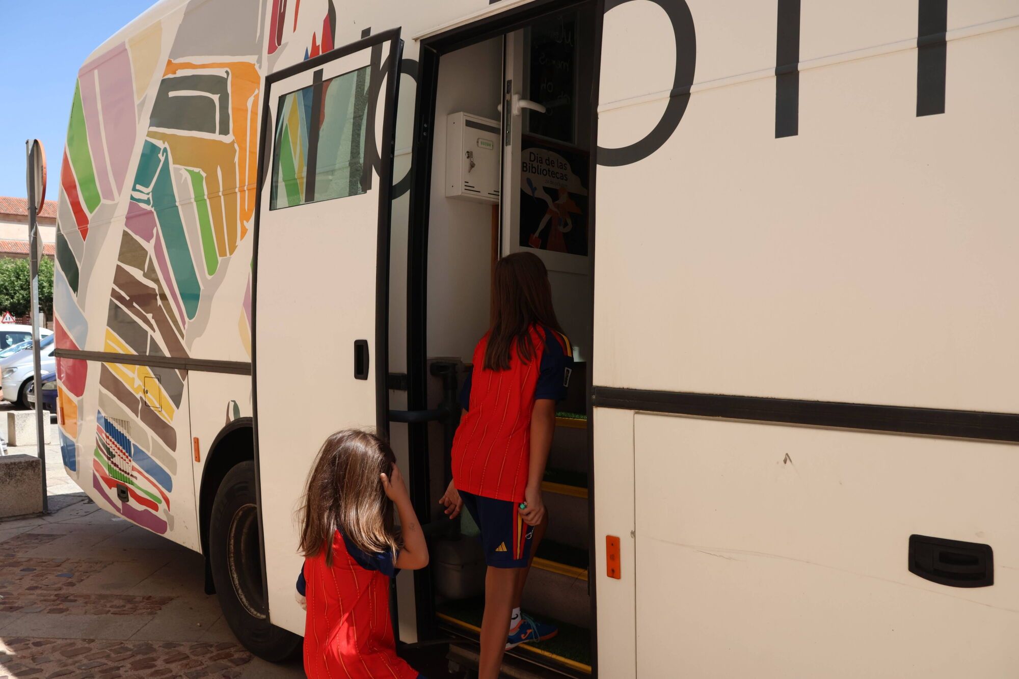 Dos menores acceden al bibliobús escolar.