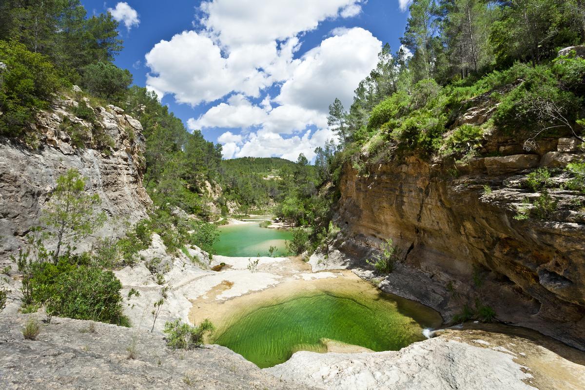 Un paraje fluvial salpicado de pequeñas cascadas y pozas naturales sobre roca caliza.