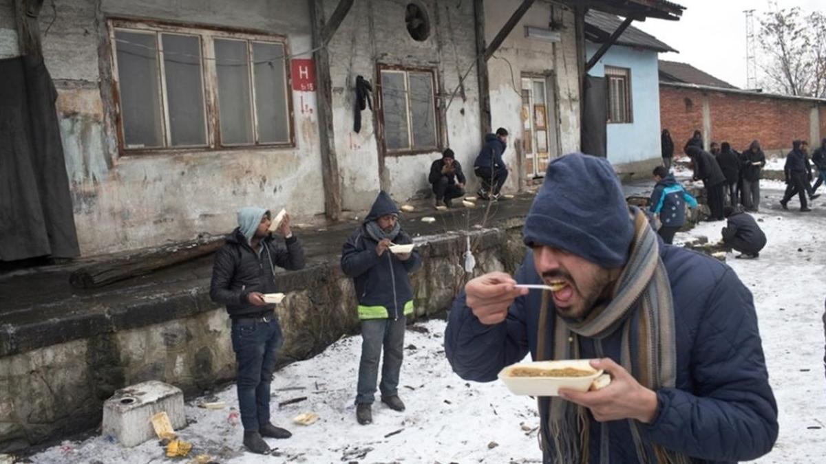 Refugiados comen en el exterior de un almacén abandonado en Belgrado.