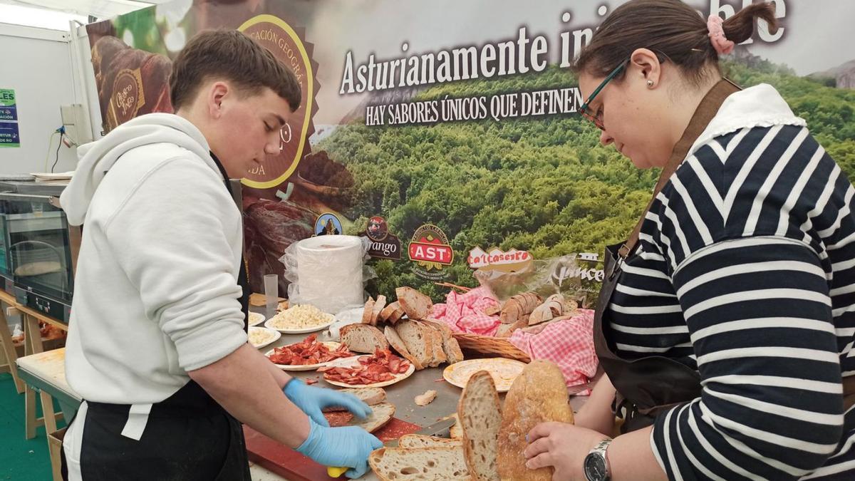 Pelayo Menéndez y Cristina Suárez preparan unas tostas con chosco de Tineo, ayer, en la Feria de Muestras. | S. A.