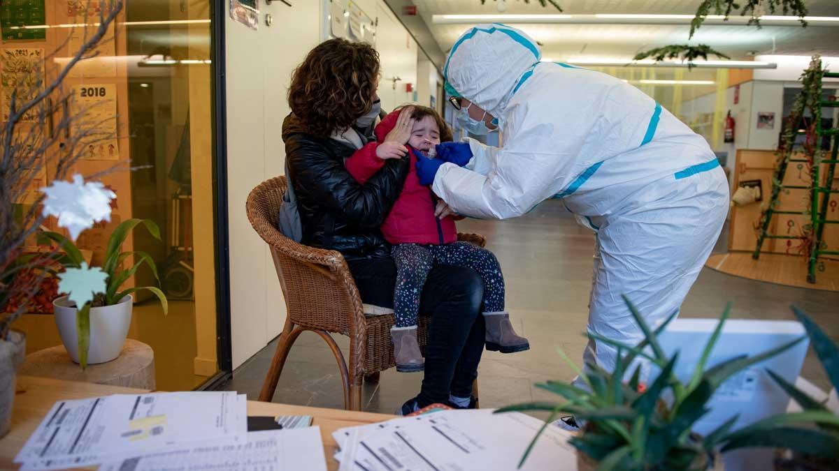 Un técnico sanitario hace una PCR a una niña de 2 años, tras detectarse un caso positivo en su guardería