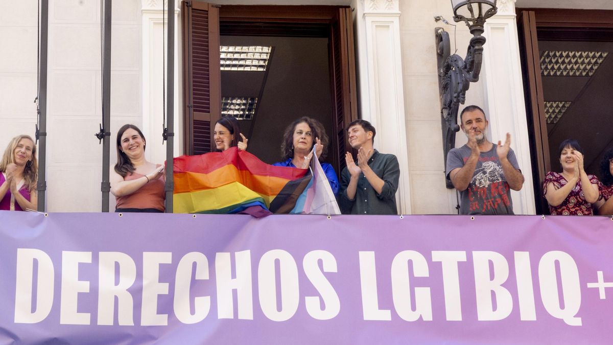 Rita Maestre y miembros de Más Madrid sosteniendo la enseña LGTBI en el balcón de los grupos.