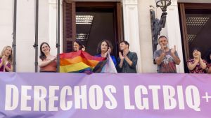 Rita Maestre y miembros de Más Madrid sosteniendo la enseña LGTBI en el balcón de los grupos.