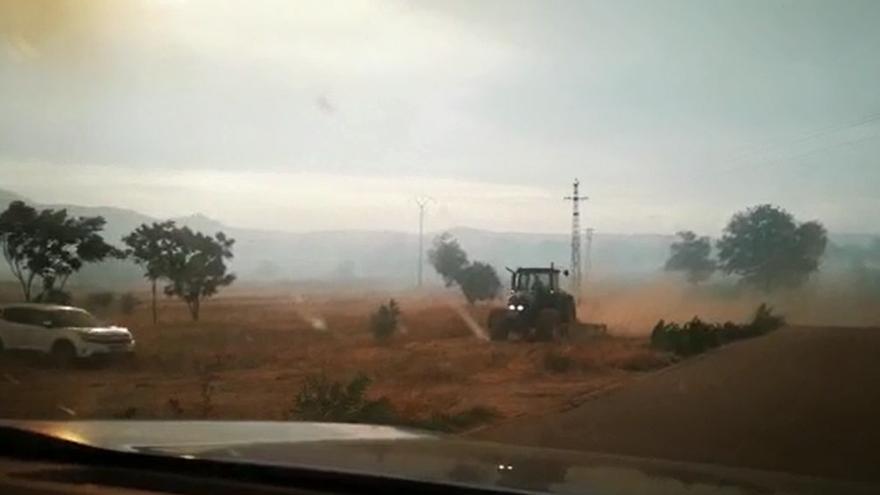 Varios agricultores, labrando los campos para hacer una línea de defensa contra el fuego