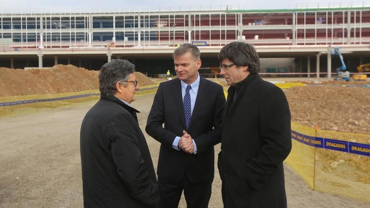 El president de la Generalitat, Carles Puigdemont; el director general de opreciones de Amazon, Fred Pattje (centro); y el alcalde de El Prat, Lluís Tejedor (izquierda), en la visita a las obras del centro logístico.