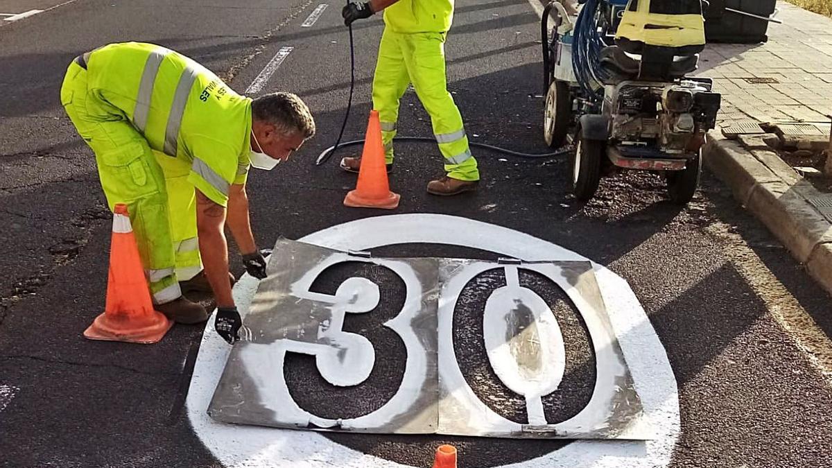 Operarios marcan en la vía el nuevo límite de velocidad.