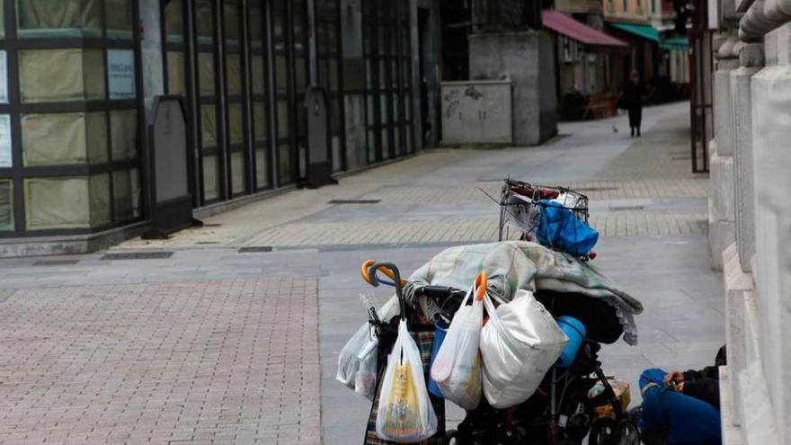 Una persona pidiendo limosna en el centro de Gijón.