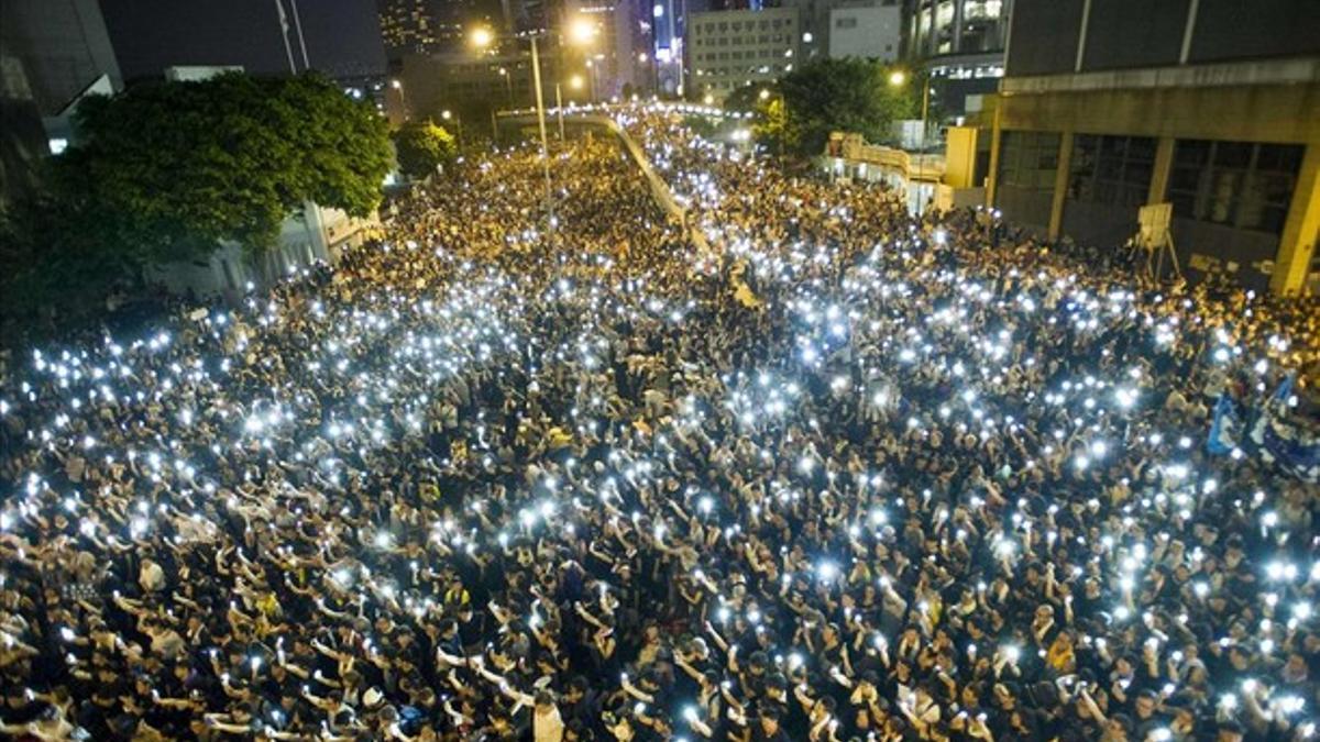 Manifestantes estudiantiles sostienen sus teléfonos  en una muestra de solidaridad durante las protestas frente a la sede del Consejo Legislativo de Hong Kong