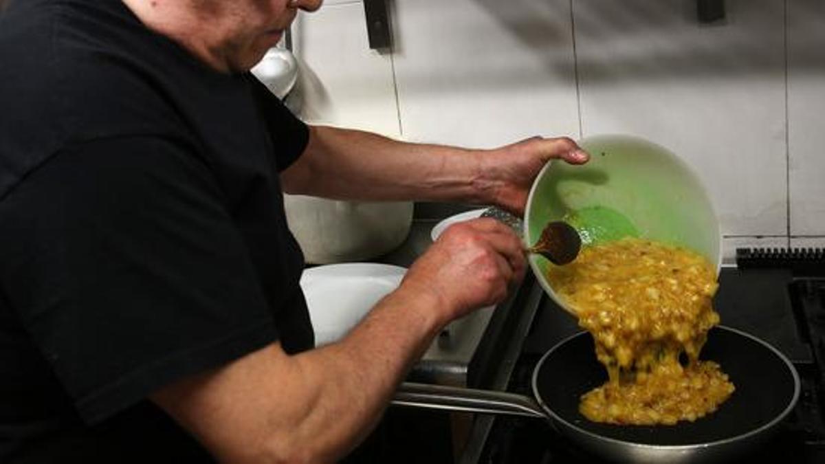 Un hombre cocinando en una sartén