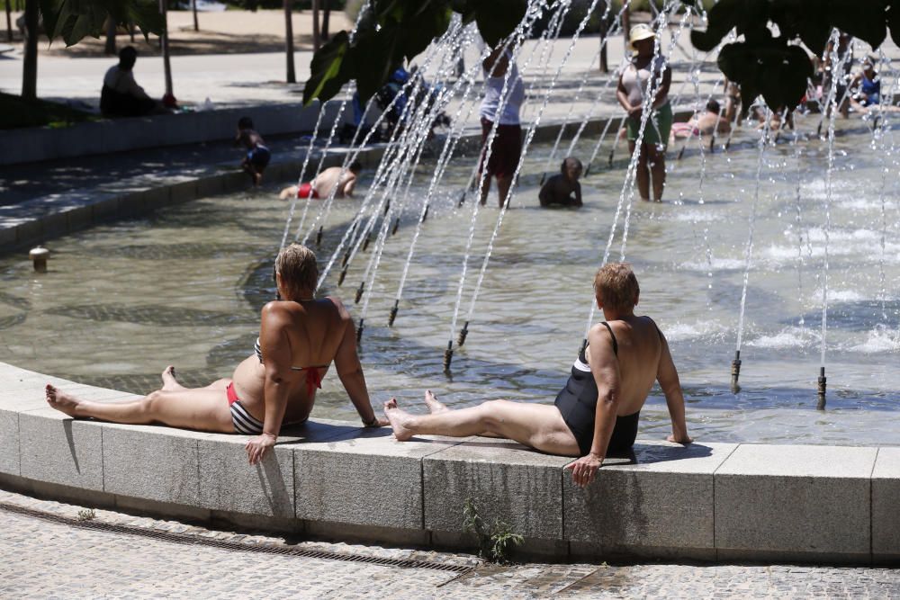 Varias personas se refrescan en una fuente