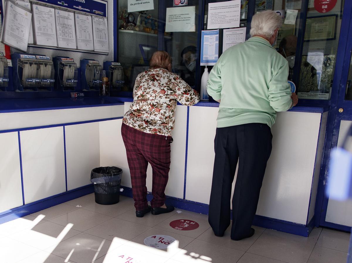 Un hombre y una mujer compran décimos en un punto de venta de Lotería Nacional.