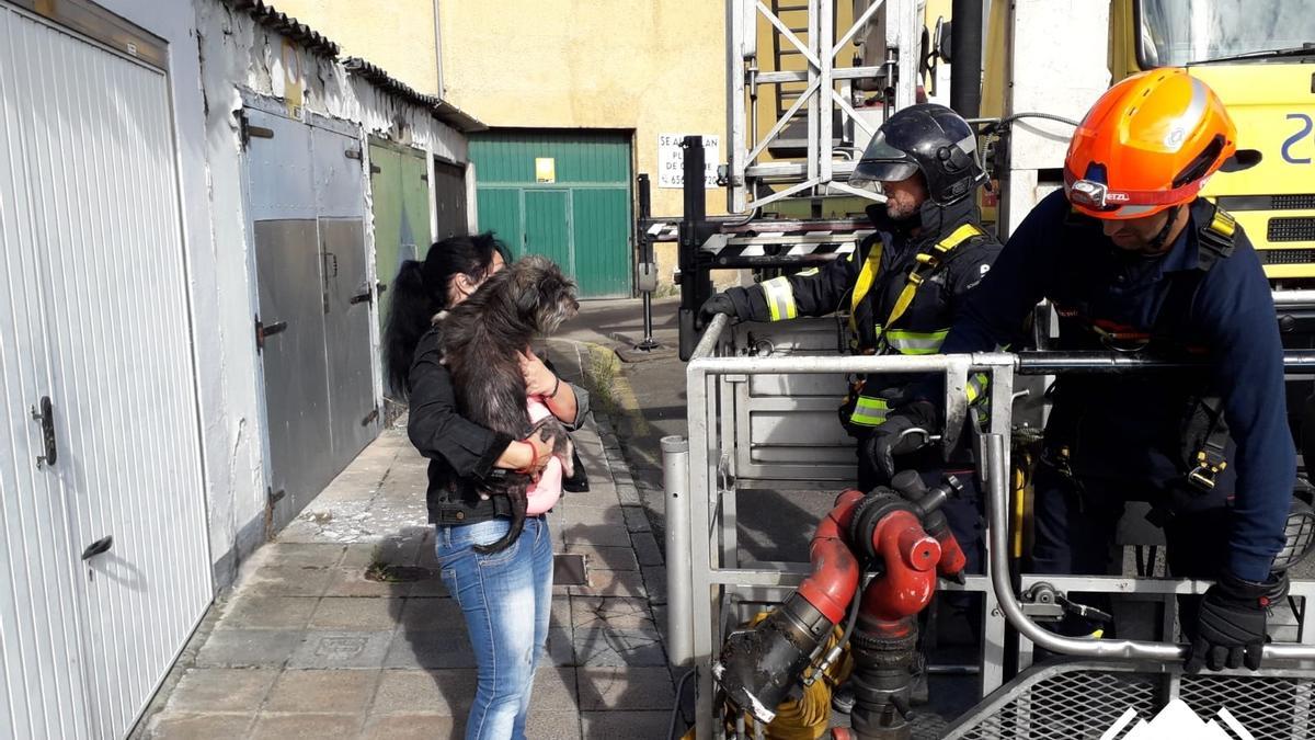 El perro, con su dueña y los Bomberos, tras ser rescatado