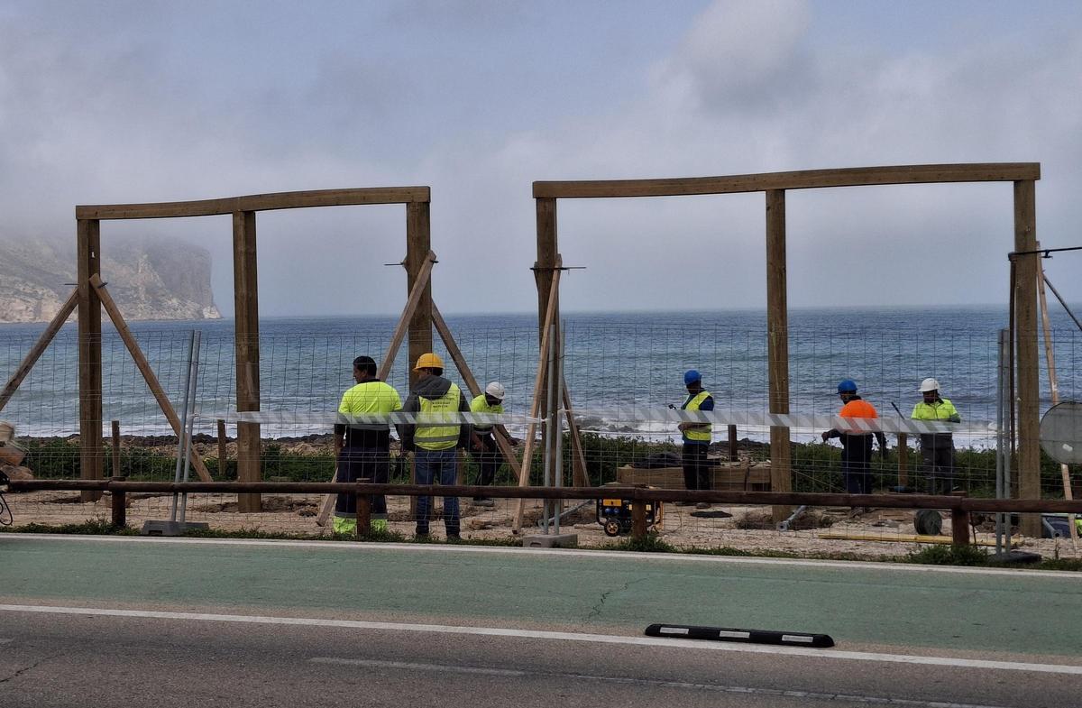 Los operarios colocan los pórticos que darán acceso a este litoral de gran valor botánico e histórico