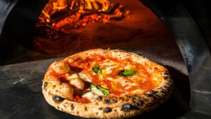 Una pizza margarita cocinada en un horno de leña.
