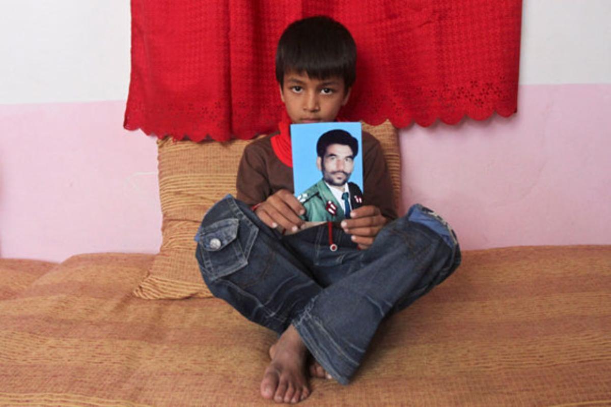 Un nen de 7 anys sosté la fotografia del seu pare assassinat en un atemptat suïcida el 19 de setembre a Kabul (Afganistan).