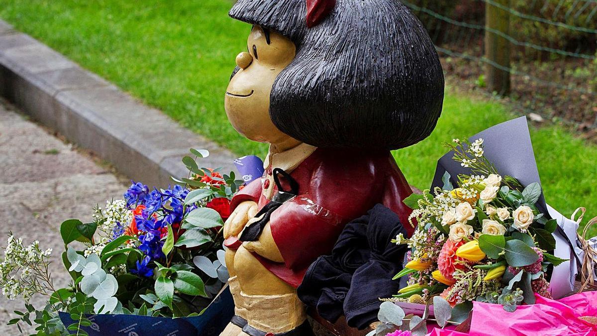 Ramos de flores junto a la estatua de su personaje más conocido. | A. M.