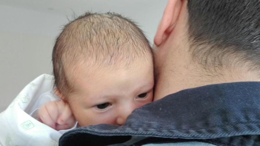 Una niña recién nacida en brazos de su padre.